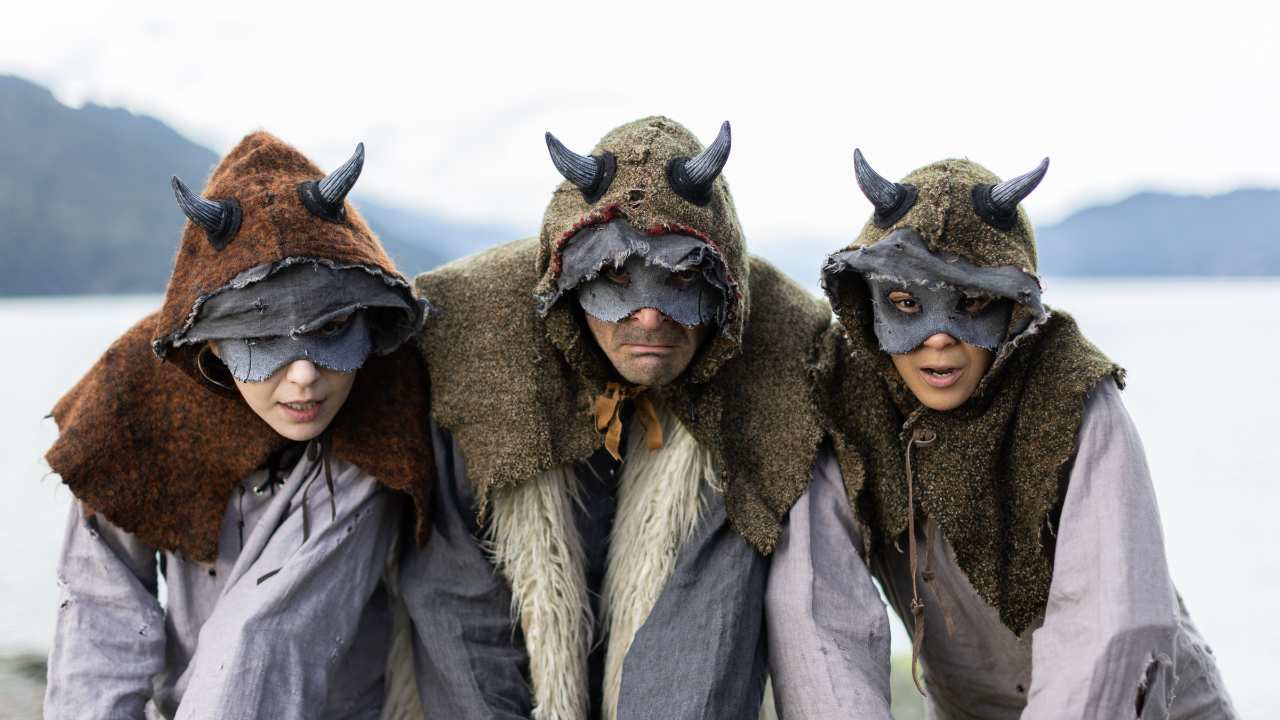 three people with hoods, horns and masks